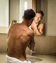 Shirtless young man examining his face in bathroom mirror Royalty Free Stock Photo