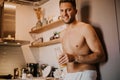 Shirtless hipster man drinking orange juice in the kitchen while leaning on the counter Royalty Free Stock Photo