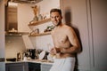 Shirtless hipster man drinking orange juice in the kitchen while leaning on the counter Royalty Free Stock Photo