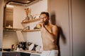 Shirtless hipster man drinking orange juice in the kitchen while leaning on the counter Royalty Free Stock Photo