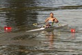 A shirtless hispanic man with chest tattoo is rowing in a white single scull