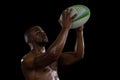 Shirtless male athlete catching rugby ball