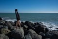 Shirtless man doing handstand on rocks by the sea. Royalty Free Stock Photo