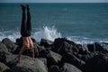 Shirtless man doing handstand on rocks by the sea. Royalty Free Stock Photo