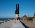 Shirtless man doing a handstand on the seashore. Royalty Free Stock Photo