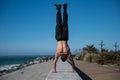 Shirtless man doing a handstand on the seashore. Royalty Free Stock Photo