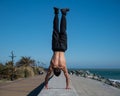 Shirtless man doing a handstand on the seashore. Royalty Free Stock Photo