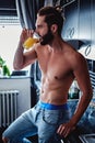 Shirtless man drinking orange juice in the kitchen Royalty Free Stock Photo