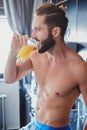 Shirtless man drinking orange juice in the kitchen