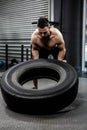 Shirtless man flipping heavy tire