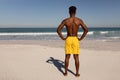 Shirtless man with hands on hip standing on beach in the sunshine Royalty Free Stock Photo