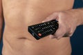 Shirtless man holds remote control in hand, isolated over blue background Royalty Free Stock Photo