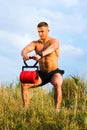 Masculine man exercising outside with a weight