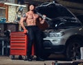 Shirtless mechanic in a garage.