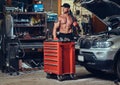 Shirtless mechanic in a garage.