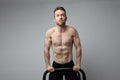 Shirtless muscular athlete doing push-up on push up bars. Royalty Free Stock Photo