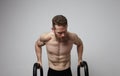 Shirtless muscular athlete doing push-up on push up bars. Royalty Free Stock Photo