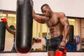 Shirtless muscular male boxer resting next to punching bag