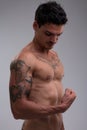 Handsome, muscular, tattooed man observes flexed bicep Royalty Free Stock Photo