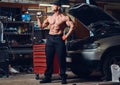 Shirtless mechanic in a garage.