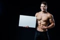 Shirtless muscular young man standing holding a blank horizontal white banner pointing finger at the copyspace for your Royalty Free Stock Photo