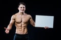 Shirtless muscular young man standing holding a blank horizontal white banner pointing finger at the copyspace for your Royalty Free Stock Photo