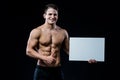 Shirtless muscular young man standing holding a blank horizontal white banner pointing finger at the copyspace for your Royalty Free Stock Photo