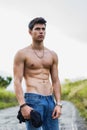 Shirtless muscular young man walking on rural road