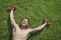 Shirtless, smiling, muscular man lying in grass with dumbbells in Beijing, view from above Royalty Free Stock Photo