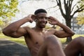 Shirtless young black man with wireless earphones doing sit-ups while smiling in park Royalty Free Stock Photo