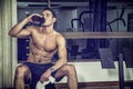 Shirtless young man drinking protein shake in gym
