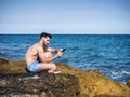 Young man on beach reading with ebook reader Royalty Free Stock Photo