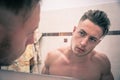 Shirtless young man examining his face in bathroom mirror Royalty Free Stock Photo