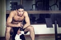 Shirtless young man holding protein shake in gym