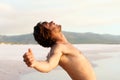 Shirtless young man leaning back by beach Royalty Free Stock Photo