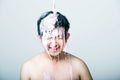 Shirtless young man with pink paint falling on his head against gray background