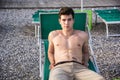 Shirtless Young Man Sunbathing in Lounge Chair on Beach Royalty Free Stock Photo