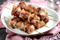 Shish kebab from pork in bacon on wooden skewers roasted on a cast-iron frying pan.