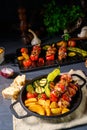 A Shish kebab with various vegetables and spice country potatoes