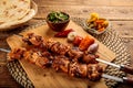 Shish Tawook kebab with pickle and bread served in a dish isolated on wooden background side view