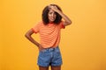 Shit I am in trouble. Concerned anxious cute dark-skinned woman in trendy t-shirt and shorts clenching teeth with guilty