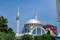 Silver dome and two minarets of the Ebu Beker Mosque against the blue sky in Shkoder. Facade of