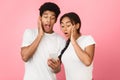 Shock content. Couple using smartphone, pink background