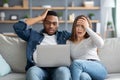 Shock Content. Frustrated interracial couple looking at laptop screen and touching heads