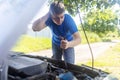 Timing belt break. Man near hood of car is looking for a malfunction due to which the engine does not work. Driver is holding a Royalty Free Stock Photo