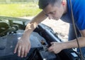 Timing belt break. Man near hood of car is looking for a malfunction due to which the engine does not work. Driver is holding a Royalty Free Stock Photo