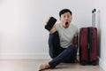 Shock and surprise face of man using mobile phone application for travel, sitting with his baggage or luggage. Royalty Free Stock Photo