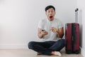 Shock and surprise face of man using mobile phone application for travel, sitting with his baggage or luggage. Royalty Free Stock Photo