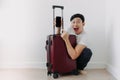 Shock and surprise face of man using mobile phone application for travel, sitting with his baggage or luggage. Royalty Free Stock Photo