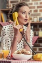 shocked adult housewife talking by vintage wired phone Royalty Free Stock Photo